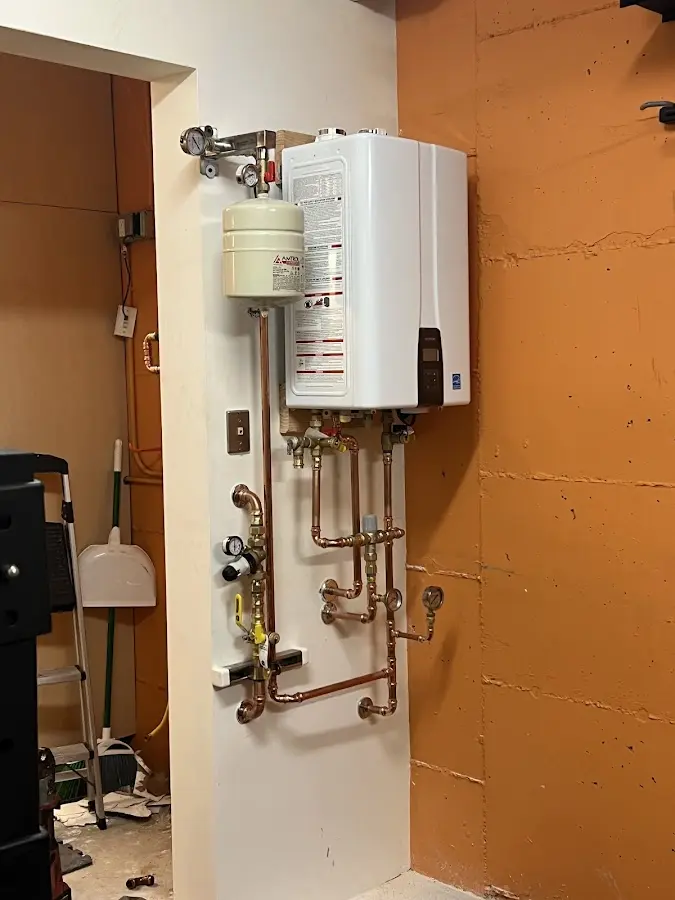 Plumbing technician inspecting water heater connections in Middle Valley
